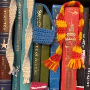 Crochet scarves, books, purse on bookshelf